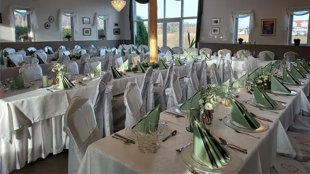 Elegant restaurant med dekket bord, hvite duker og grønne servietter, klar for fest eller arrangement.