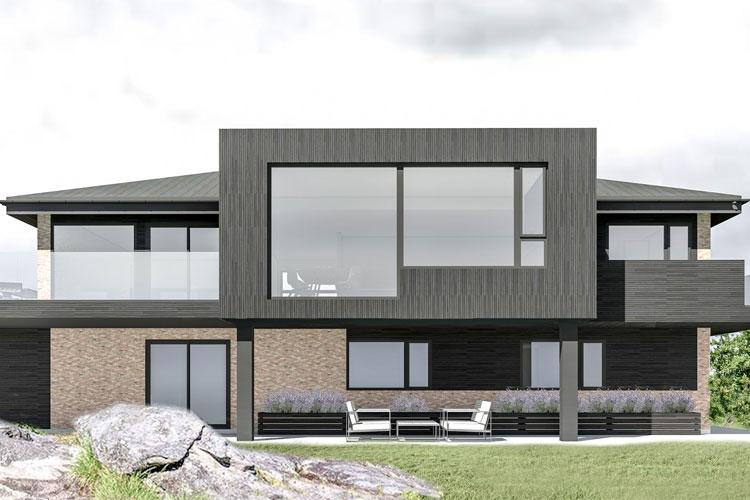 Moderne hus med store vinduer, balkong og steinbelagt uteområde, omgitt av grønt landskap.