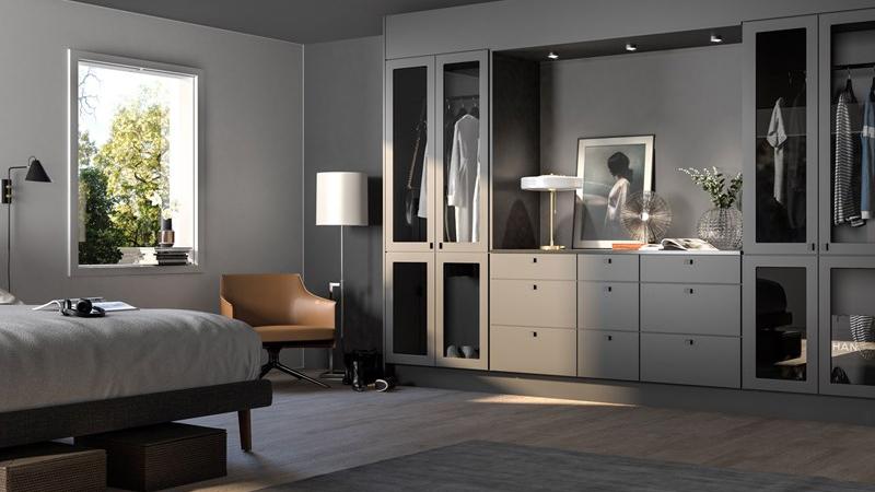 Moderne soverom med en seng, garderobeskap, lampe og en stol, samt naturlig lys fra vinduet.