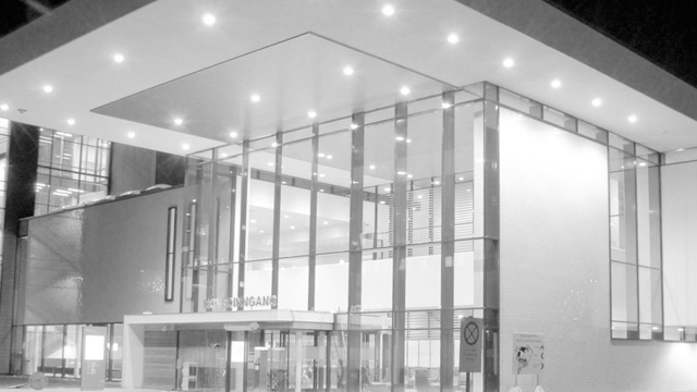 Moderne bygning med glassfasade og takbelysning, inngangspartiet er tydelig synlig om natten.