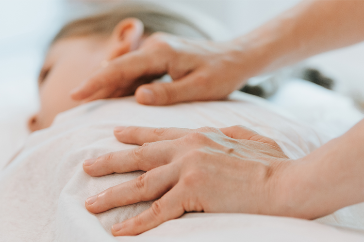 En person får massasje med hender som trykker forsiktig på ryggen.