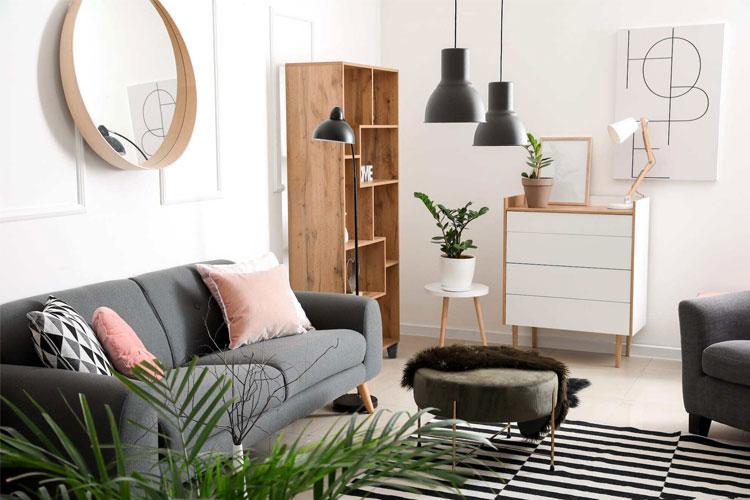 Moderne stue med grå sofa, trehyller, planter og stilige lamper i en lys atmosfære.