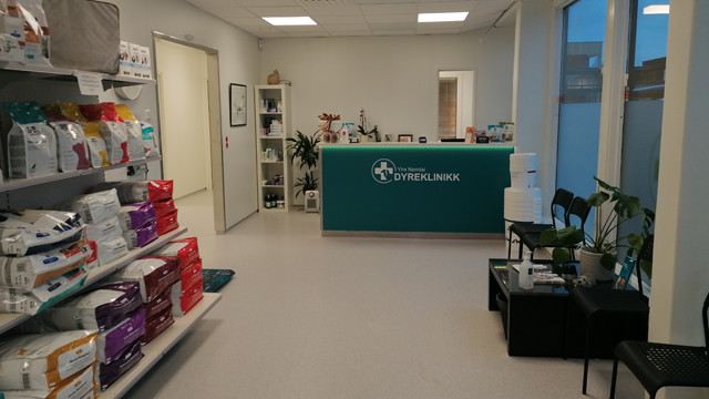 Moderne dyreklinikk med resepsjon, hyller med dyrefôr og sitteplasser for kunder.