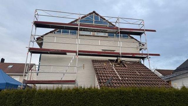 Hus med stillas rundt, under renovering, med takstein og vinduer synlige.