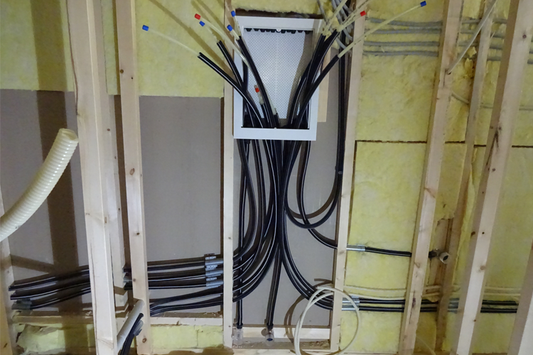 Rør og kabler installert i en vegg med isolasjon, klart for elektrisk og rørleggerarbeid.