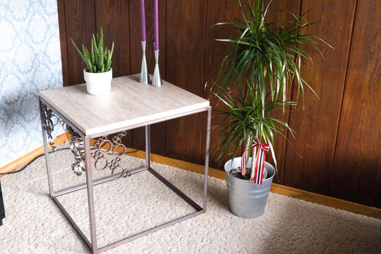 Moderne stuebord med metallramme, planter i potter og dekorative lysestaker på en beige teppe.