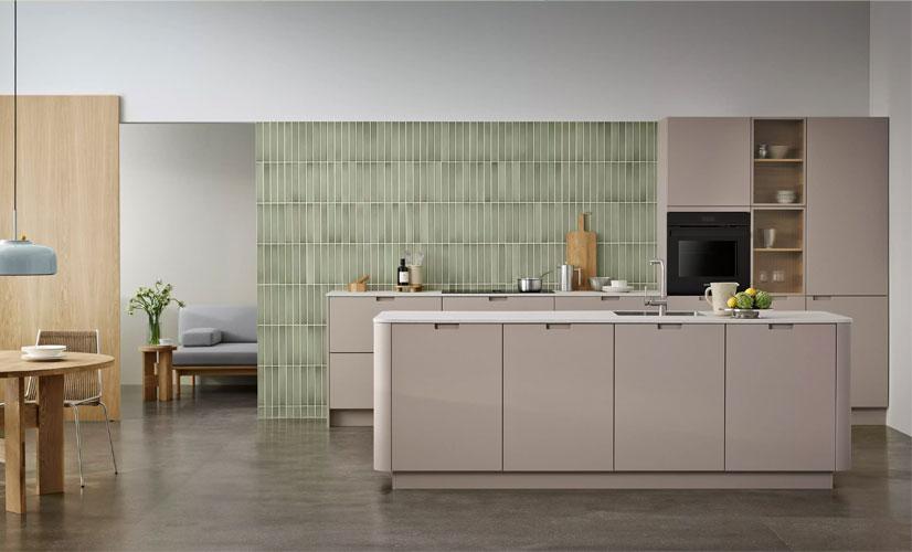 Moderne kjøkken med lys beige skap, grønn flisvegg og spisebord i tre.