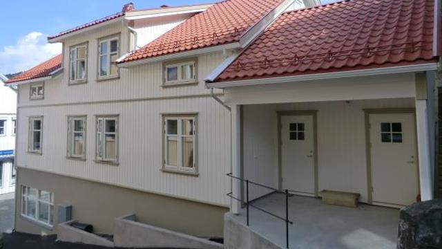 En moderne bygning med hvit fasade og rød takstein, med inngangspartier og vinduer.