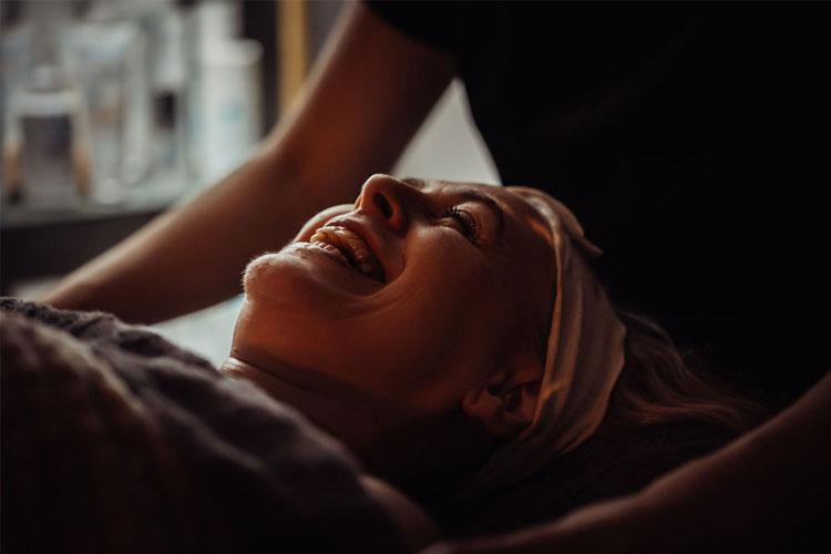 Kvinne som smiler mens hun får ansiktsbehandling i et spa, med en behagelig atmosfære rundt seg.