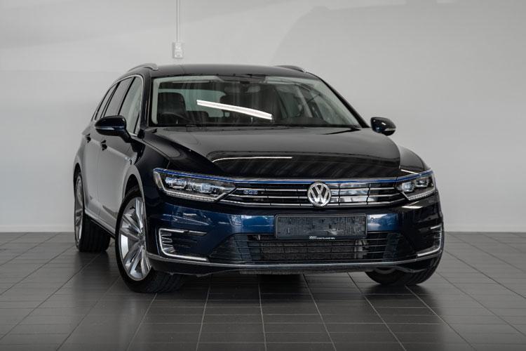 En svart Volkswagen Passat stasjonsvogn står på et flislagt gulv i en bilutstilling.