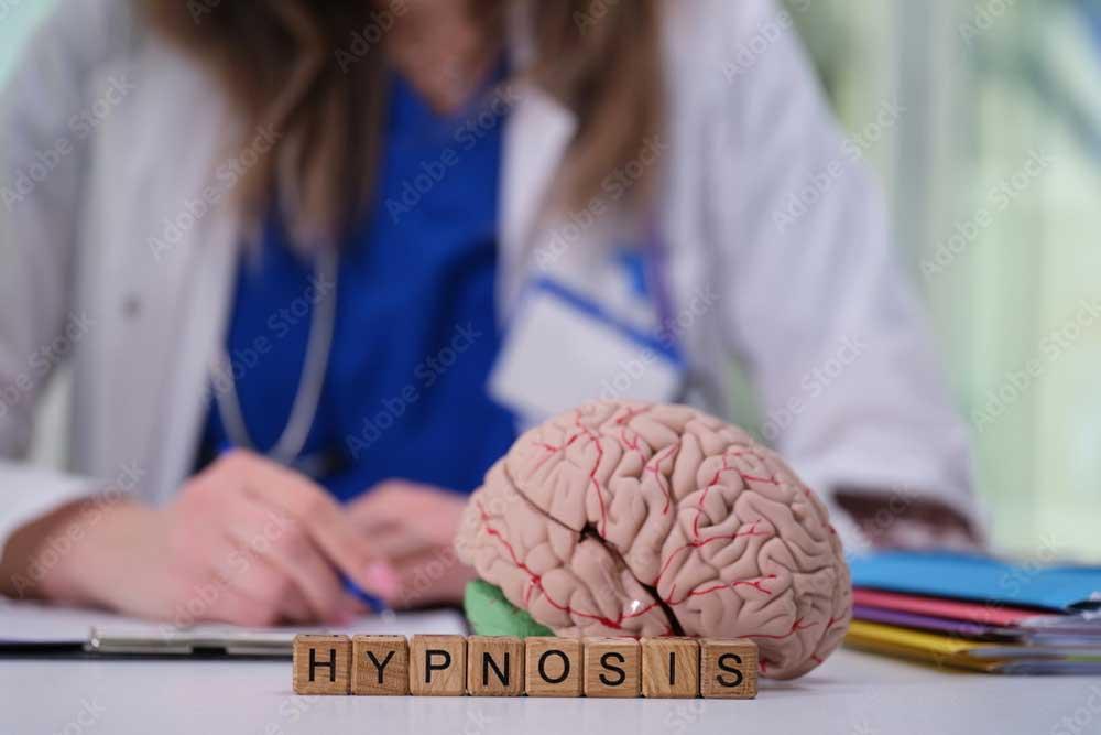 En hjerne med bokstavene "HYPNOSIS" foran, mens en person i hvit frakk skriver på et notat.