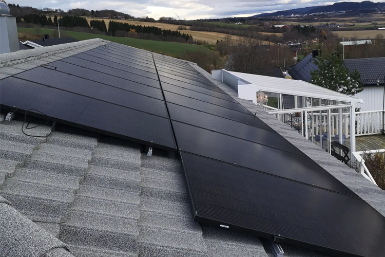 Solcellepaneler installert på taket av et hus med landskap i bakgrunnen.