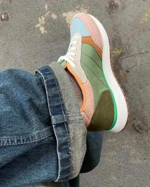 Fargerik sneaker med grønn, rosa og blå detaljer, iført med jeans med oppbrettede ben.