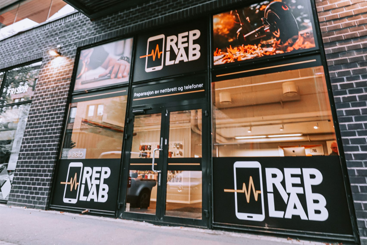 Butikken RepLab med store vinduer og logo, som tilbyr reparasjon av mobiltelefoner og elektronikk.