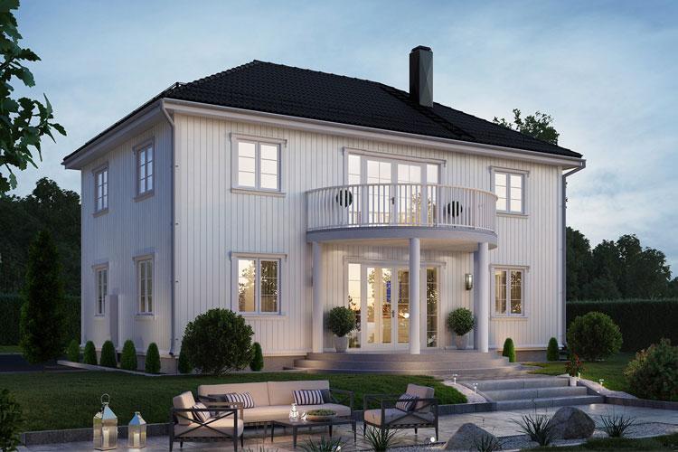 Moderne, hvitt hus med balkong og hage, belyst om kvelden, omgitt av trær og steinlagte stier.