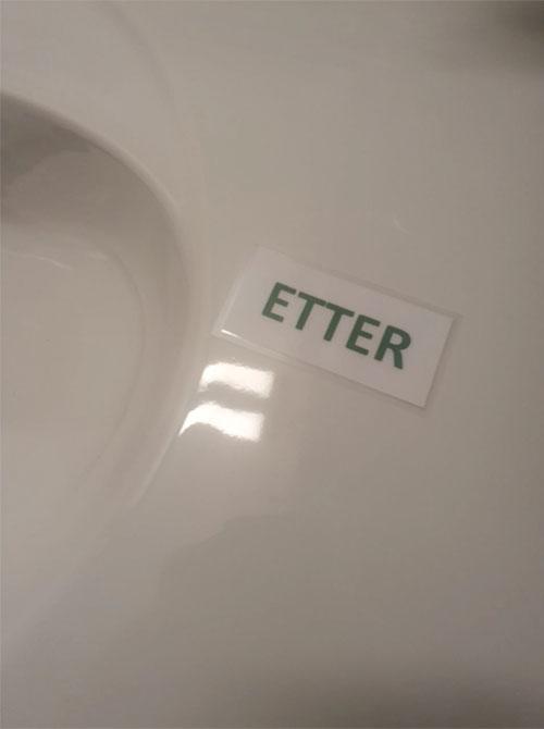 Etikett med teksten "ETTER" plassert på en hvit overflate.