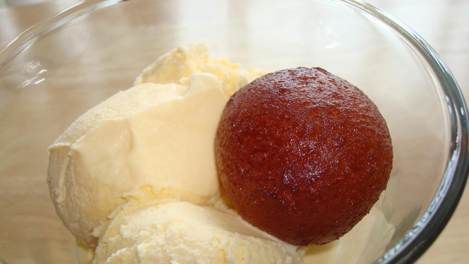 En skål med vaniljeis og en gulab jamun, en indisk dessert laget av fritert deig og sirup.