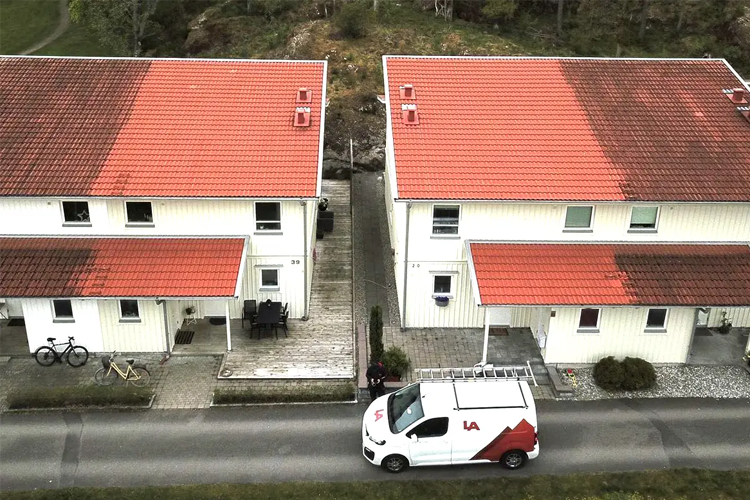 To hus med rød takstein og hvite vegger, med en varebil parkert foran.