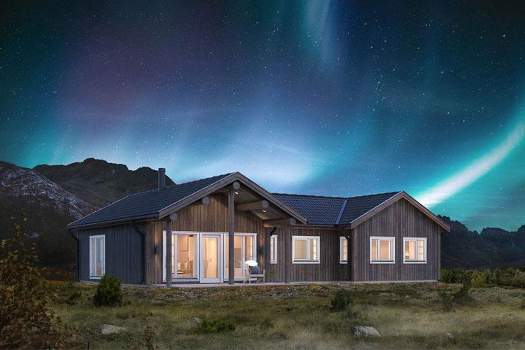 Moderne hytte med store vinduer under nordlyset i en naturskjønn fjellandskap.
