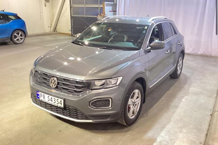 Grå Volkswagen T-Roc SUV parkert i en garasje med lys bakgrunn.