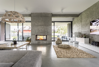 Moderne stue med betongvegg, peis, sofa, teppe og store vinduer som slipper inn naturlig lys.