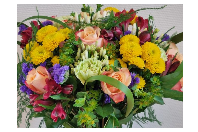 En fargerik bukett med roser, krysantemum, alstromeria og grønt bladverk.