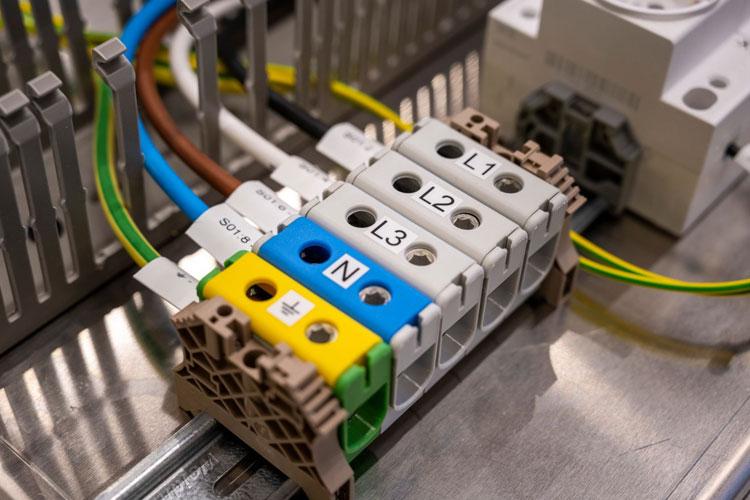 Koblingspunkt med fargede ledninger og merking for L1, L2, L3, N, og jordforbindelse i elektrisk installasjon.