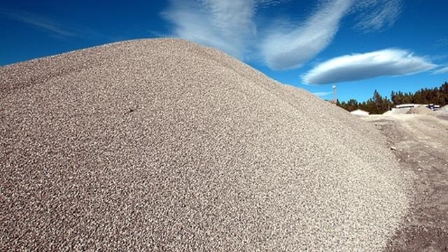 En stor haug med grus under en blå himmel med skyer.