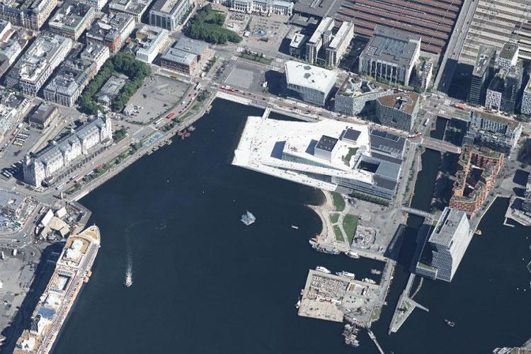 Luftbilde av havnen i Oslo med moderne bygninger, båter og en hvit bygning som huser operahuset.