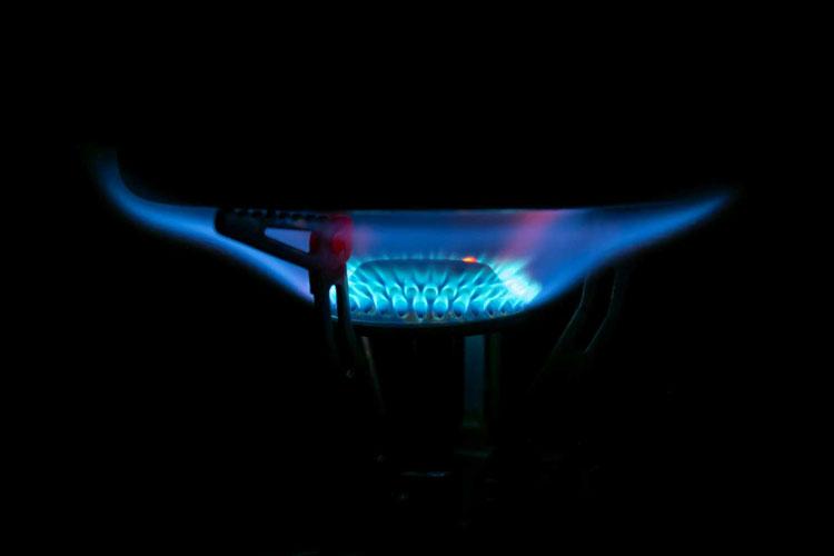 Blå flamme fra en gasskomfyr som lyser opp et mørkt rom.