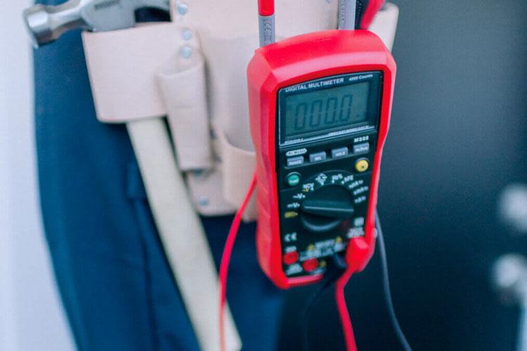 Multimeter henger på et verktøybelte, viser måling av elektrisk spenning eller strøm.