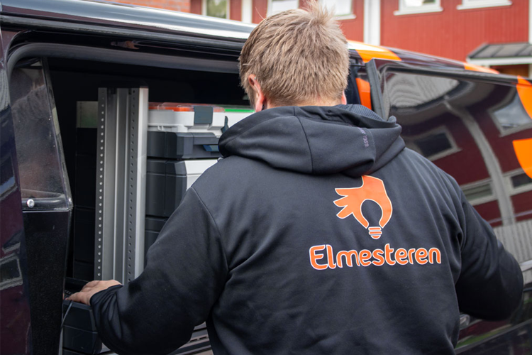 En elektriker fra Elmesteren laster ut en skriver fra en varebil.