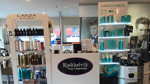 Interiør av en frisørsalong med produkter fra L'Anza og Moroccanoil, samt en disk med Kjøkkelvik-logo.