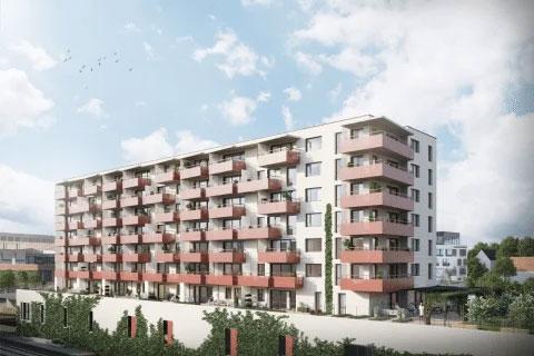 Moderne leilighetsbygg med fem etasjer og balkonger, omgitt av grøntområder og parkeringsplasser.