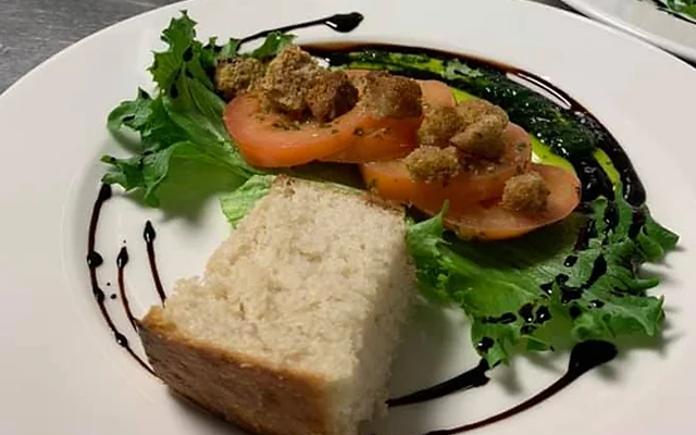 En tallerken med salat, tomater, krutonger og brød, dekorert med balsamico.