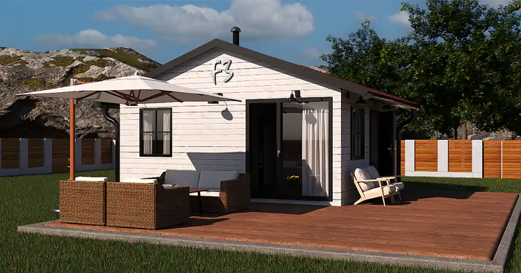 Moderne hytte med terrasse, parasoll og utemøbler, omgitt av grønt gress og trær.