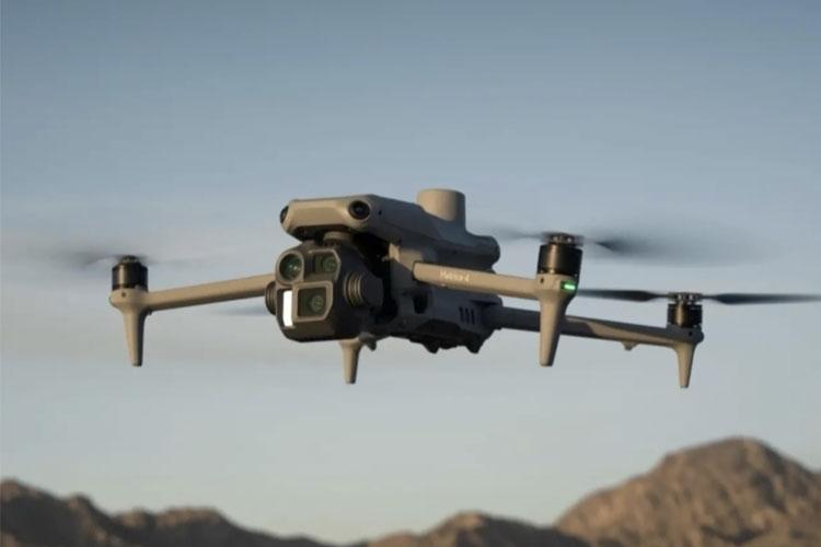 En drone flyr over et fjellandskap med klare himmel og synlige rotorblader.