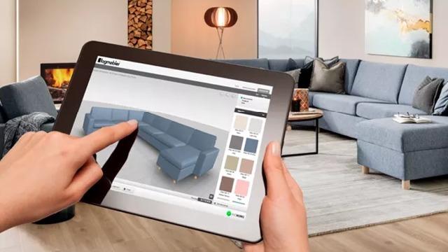 En person bruker et nettbrett for å designe en sofa i et moderne stue med peis og stilige møbler.