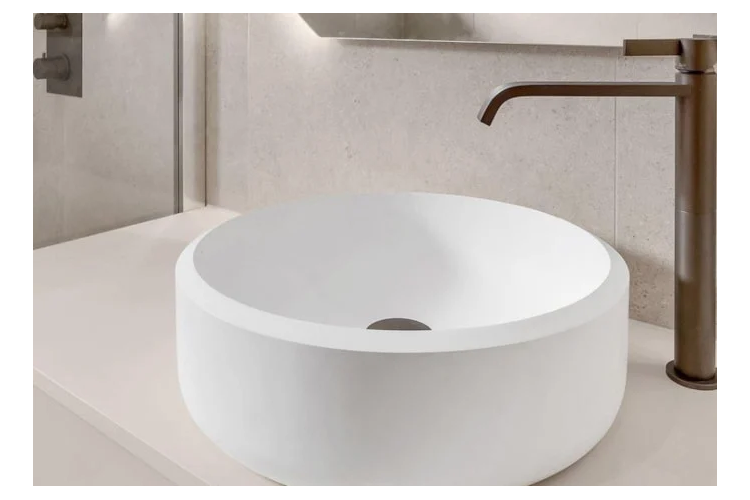 Moderne hvit servant med rund form og en stilren brun kran i et elegant baderomsmiljø.