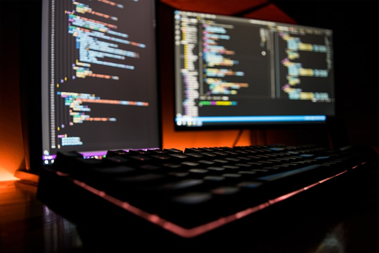 To skjermbilder med kode og et tastatur i forgrunnen, belyst av et svakt bakgrunnslys.