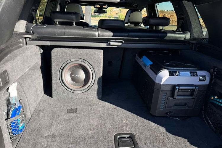Bagasjerommet i en SUV med subwoofer, kjøleboks og plass til bagasje.