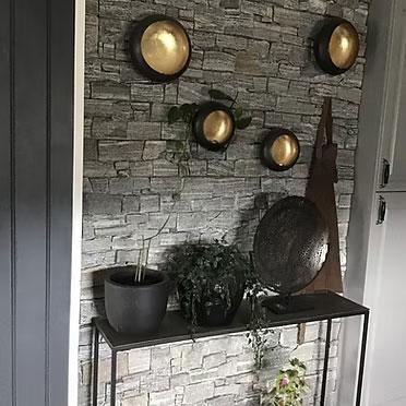 Moderne interiør med steinvegg, planter, og dekorative lamper i en stilig entré.