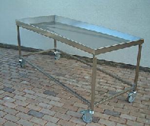 Et rustfritt stålbord med hjul, plassert på en steinlagt overflate.