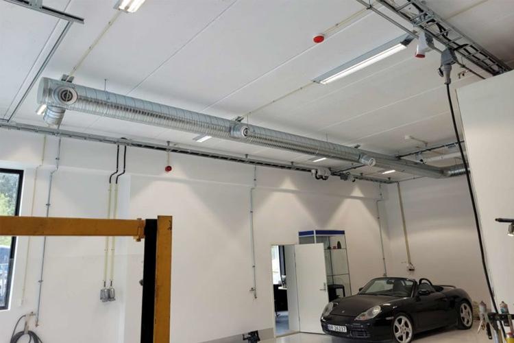 Moderne verksted med en sportsbil, takventilasjon og lys i et lyst rom.