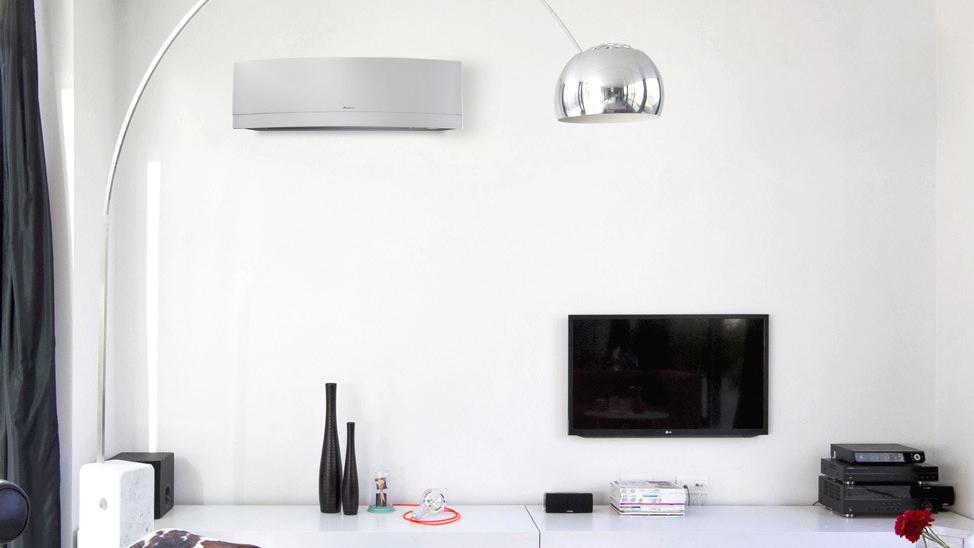 Moderne stue med veggmontert klimaanlegg, TV, svarte vaser og en stor lampe i metall.