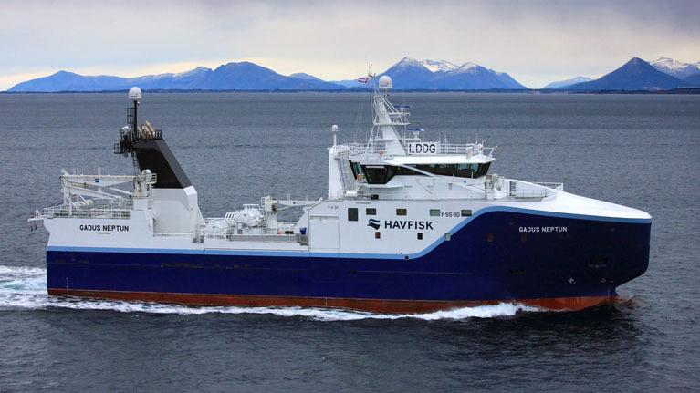 Fiskebåt med navnet "Havfisk" seiler i havet med fjell i bakgrunnen.