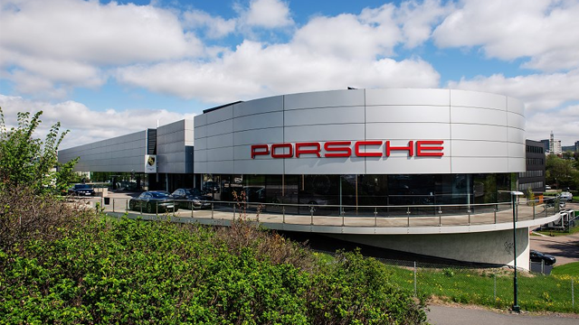 Porsche-forhandler med moderne arkitektur og biler parkert utenfor bygningen.