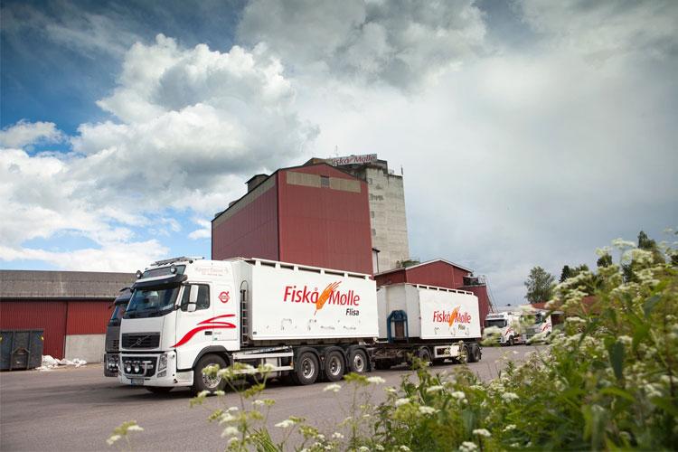 Lastebil fra Fiskå Mølle parkerer ved en stor bygning under en skyet himmel.