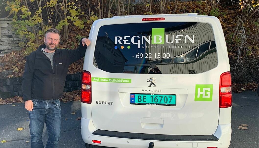 Mann står ved siden av en hvit varebil med logoen til Regnbuen og registreringsnummeret BE 16707.