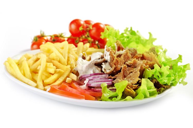 En tallerken med pommes frites, salat, tomater, løk og kjøtt med dressing.